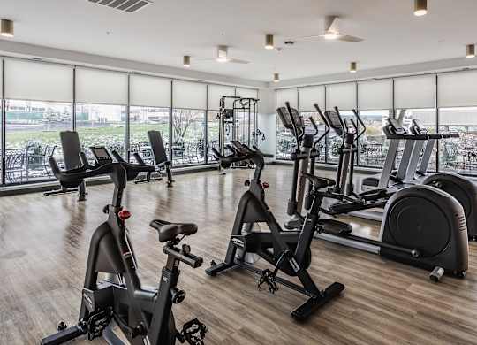A fitness center at Altura Apartments provides residents with a row of treadmills for running and elliptical machines for low-impact exercise.