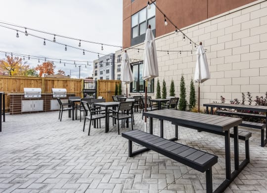 A grilling station with a selection of tables and chairs, umbrellas, and two grills.