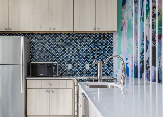 A kitchen equipped with stainless steel appliances, sleek cabinets, and decor at Madamore Apartments.