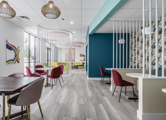 Co-working lounges at Madamore Apartments with tables and chairs, stylish decor, and windows.