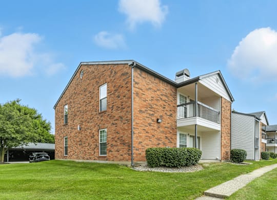 A brick house with a white garage door and a white house next to it.