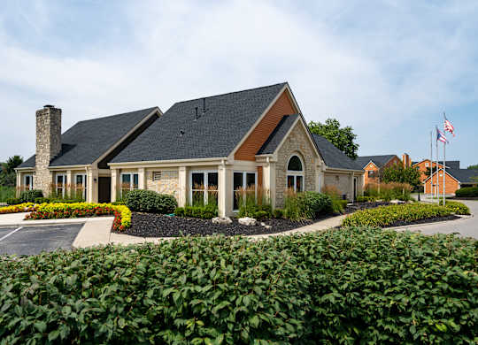 A house with a flag on the roof and a driveway in front.