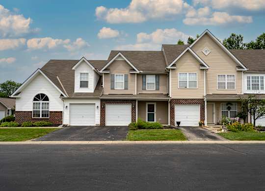 A large, two-story house with a garage is situated on a street.