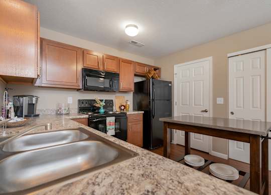 A kitchen with a refrigerator, microwave, oven, and sink.
