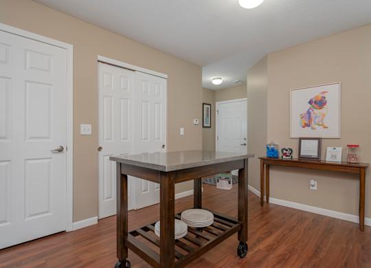 A kitchen island with a cart on wheels is in the middle of a room with two doors.
