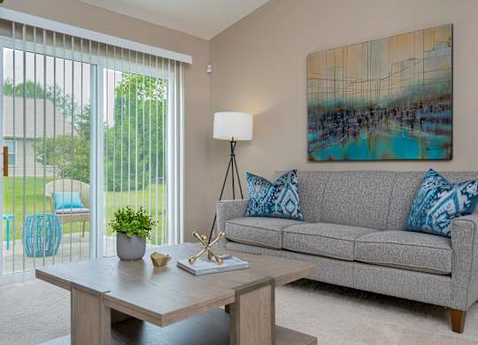A living room with a grey couch, a wooden table, and a painting on the wall.