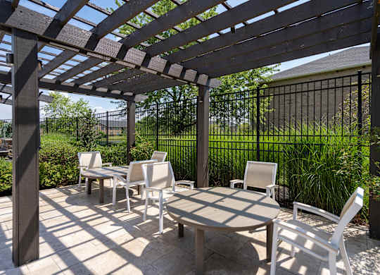 A patio with a table and chairs under a pergola.