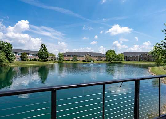 A serene lake surrounded by buildings and trees under a clear blue sky.