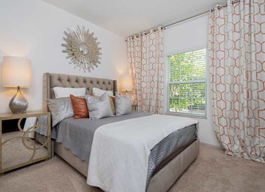 A bedroom with a large bed and a decorative sunburst mirror on the wall.
