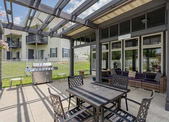 A patio with a table and chairs is covered by a roof.