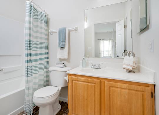 A white toilet with a blue and white striped shower curtain.