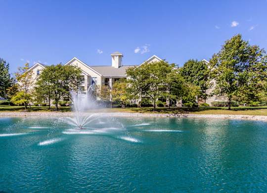 Scenic pond with a fountain surrounded by lush trees at Britton Woods 2-bedroom apartments in Dublin, OH