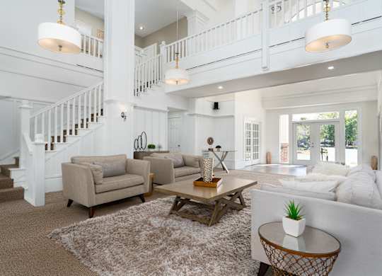 Living room with plush seating and an open staircase in a stylish apartment layout