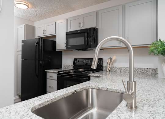 Newly renovated kitchen at Britton Woods with granite countertops, wood-style flooring, and stainless steel appliances