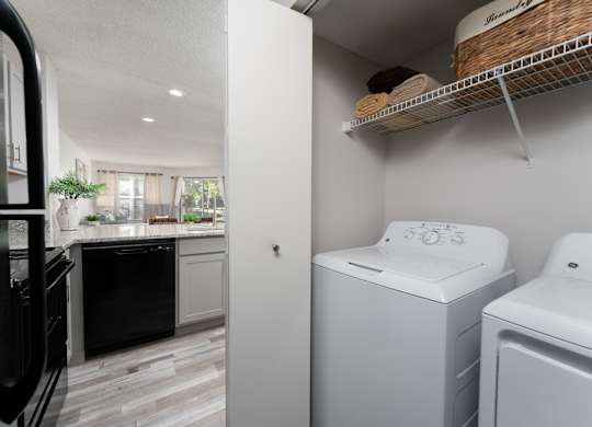 Laundry room with a white washer and dryer, adjacent to a sleek black-and-white kitchen