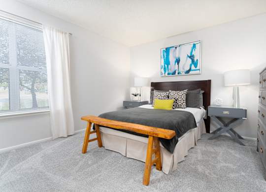 Bedroom with cozy furnishings and a large window letting in natural light