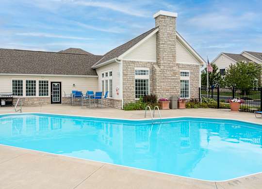 Delaware, OH Apartments Near Tanger Outlets - Carson Farms - Swimming Pool Surrounded By Patio Furniture, BBQ Area, and Lush Landscaping