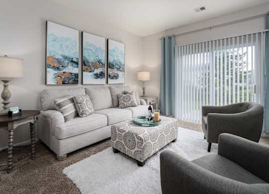 A living room with a grey couch, a coffee table, and a painting on the wall.