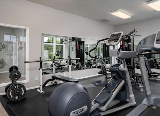 A gym with a variety of equipment including treadmills, weights, and exercise machines.