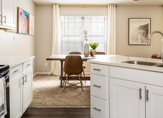 Fairway Lakes kitchen with white cabinets and hardwood-style flooring, situated next to a dining room table.