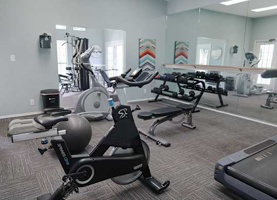 Fully equipped fitness center at The Boulevard in Florence, KY with free weights, bench press, and mirrored walls