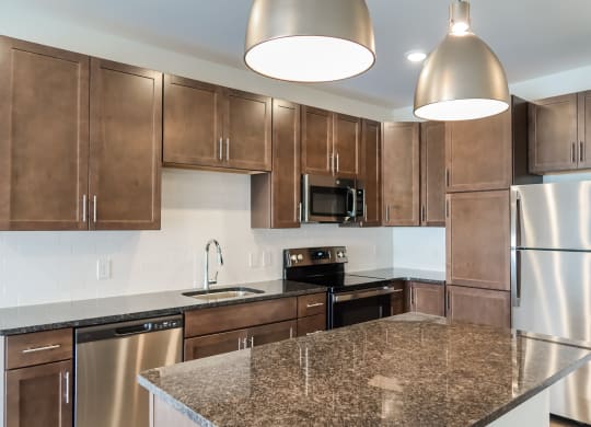 A kitchen with dark cabinets, stainless steel appliances, and an island.