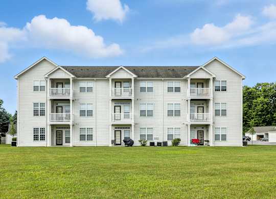 A large white apartment building with a green lawn in front.