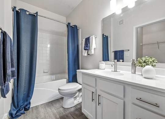 A white bathroom with a blue shower curtain.