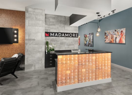 Lobby at Madamore Apartments with a desk, light fixtures, and stylish decor.
