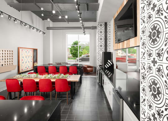 Co-working lounge with booth tables next to a beige couch, and light fixtures,