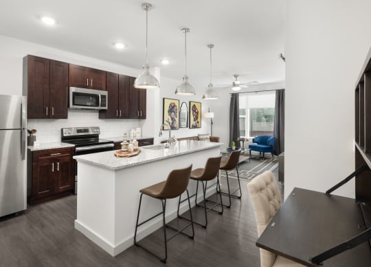 Madamore kitchen equipped with dark wood cabinets, an island with three barstools, stainless steel appliances, and hardwood-style flooring.