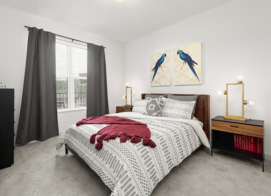 A furnished bedroom at Madamore with carpeted flooring and a window for natural light.