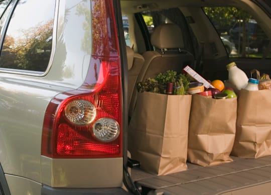 A silver car with its trunk full of groceries.