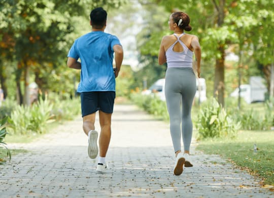 A man and a woman jogging in a park.