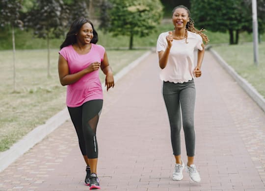 Two women jogging on a path in a park.