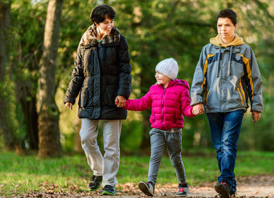 A family of three is walking in the woods.