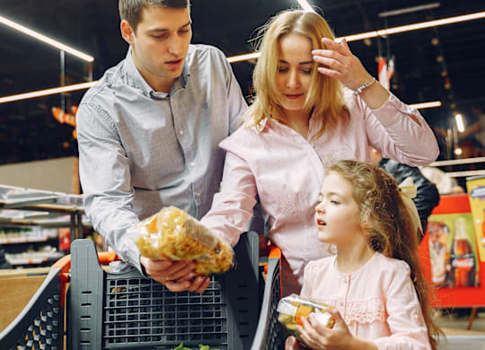 A man and a woman are shopping for groceries with a child.