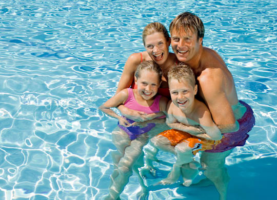 A family of four are enjoying a swim in a pool.