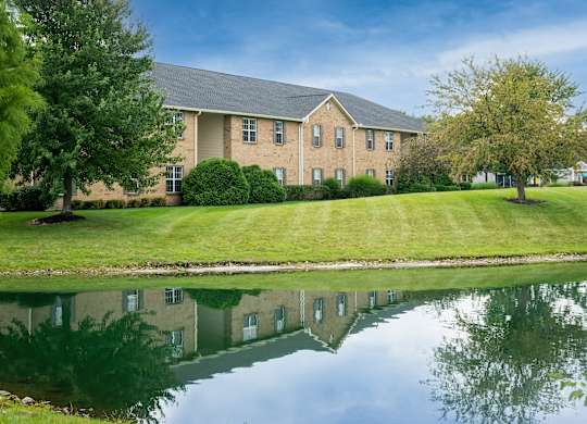 One-bedroom apartment building with landscaped grounds and pond views at The Coleman in Canal Winchester, OH