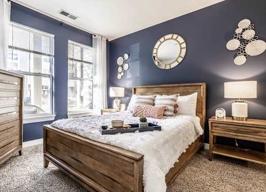 A bedroom with a large bed, a nightstand, and a window.