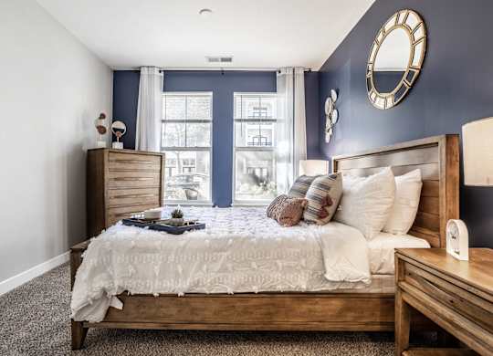 A bedroom with a large bed, a nightstand, and a window with curtains.