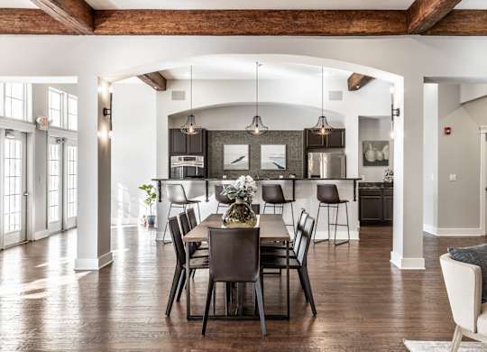 A dining room with a table set for six with a view of the kitchen.