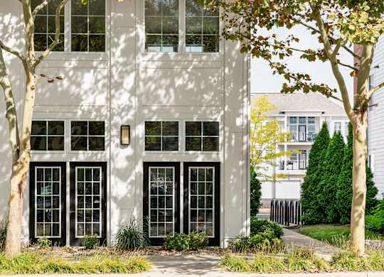 A white building with black windows and trees in front.
