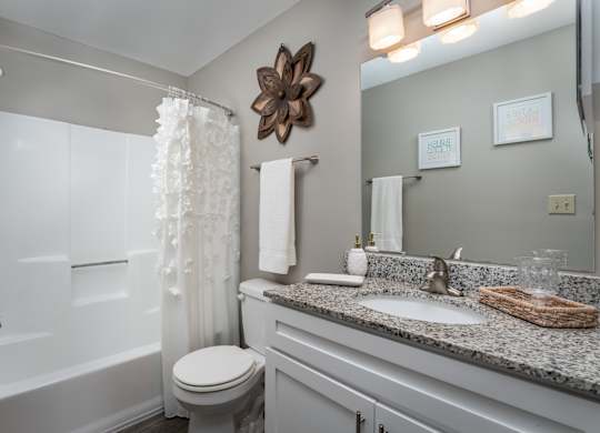 A bathroom at The Oaks with a vanity and a mirror, a white tub, and stylish decor.