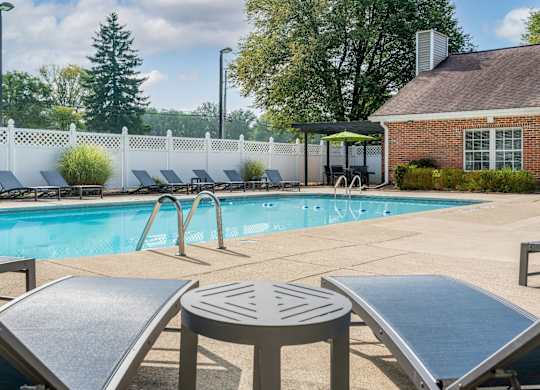 The Oaks swimming pool surrounded by chairs and a white fence.