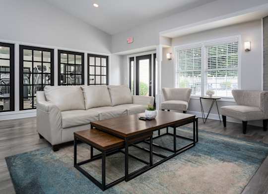 Community clubhouse at The Oaks with a couch and two chairs, next to a fitness center.