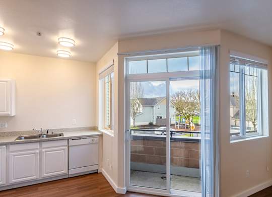 A kitchen with white cabinets and a view of the outside through the glass doors.