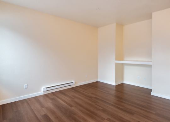 A room with wooden flooring and a wall-mounted air conditioner.