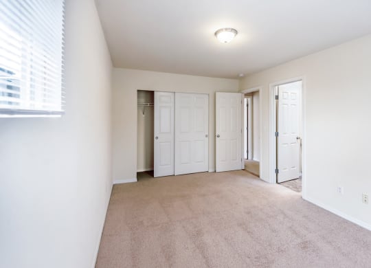a spacious living room with white walls and carpet and white doors