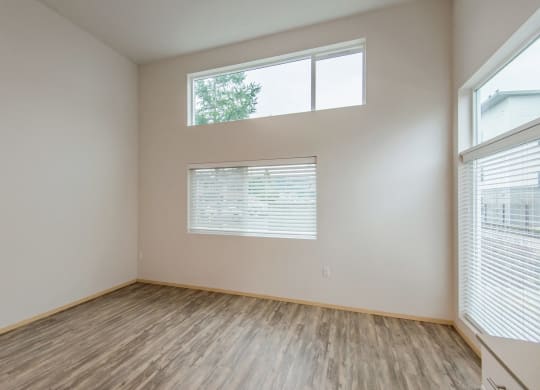 the spacious living room with large windows and wood flooring